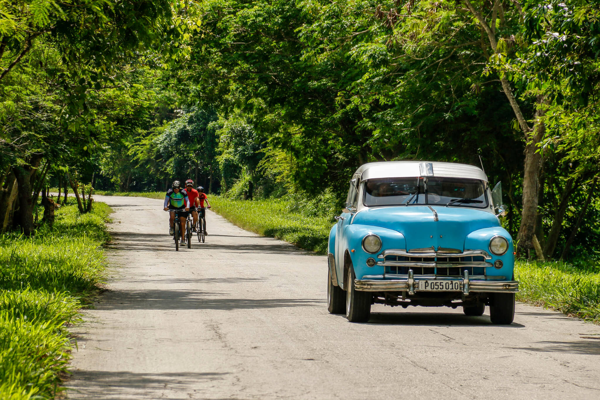 Cycling Group in Rural Cuba along with Classic American Car