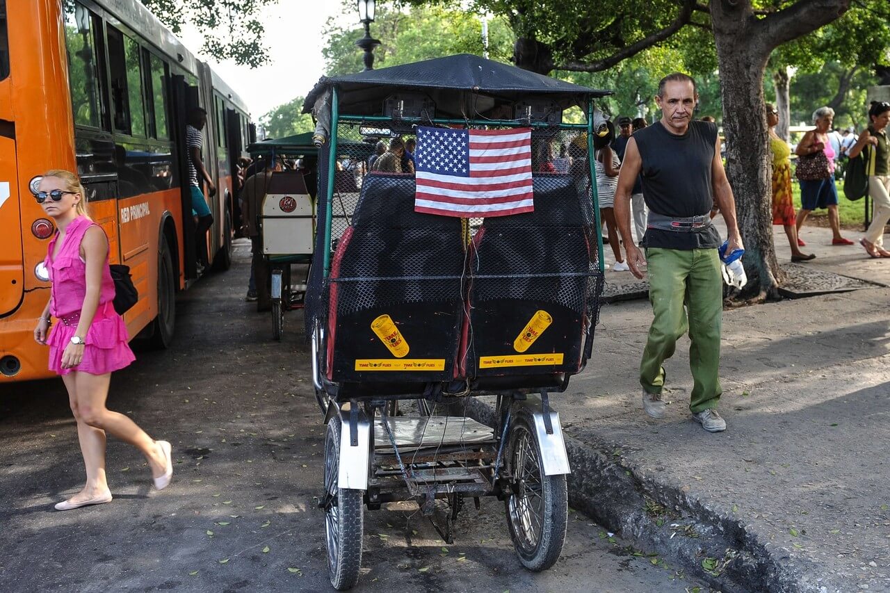 cycling vehicle like a tuk tuk with the american flag behind it